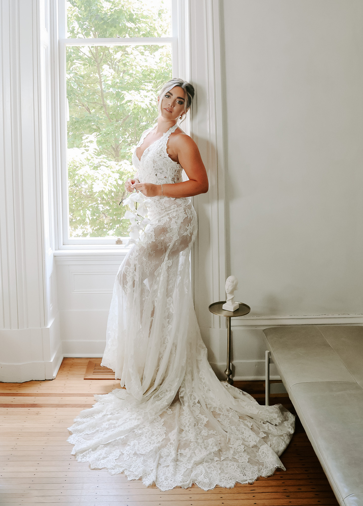 a bride poses in a wedding dress in front of a window