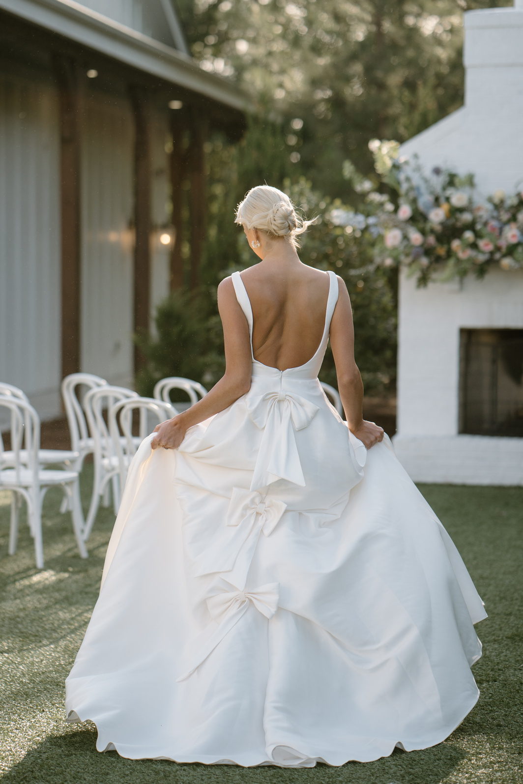 the back of a bride's wedding dress with bows in front of a fireplace