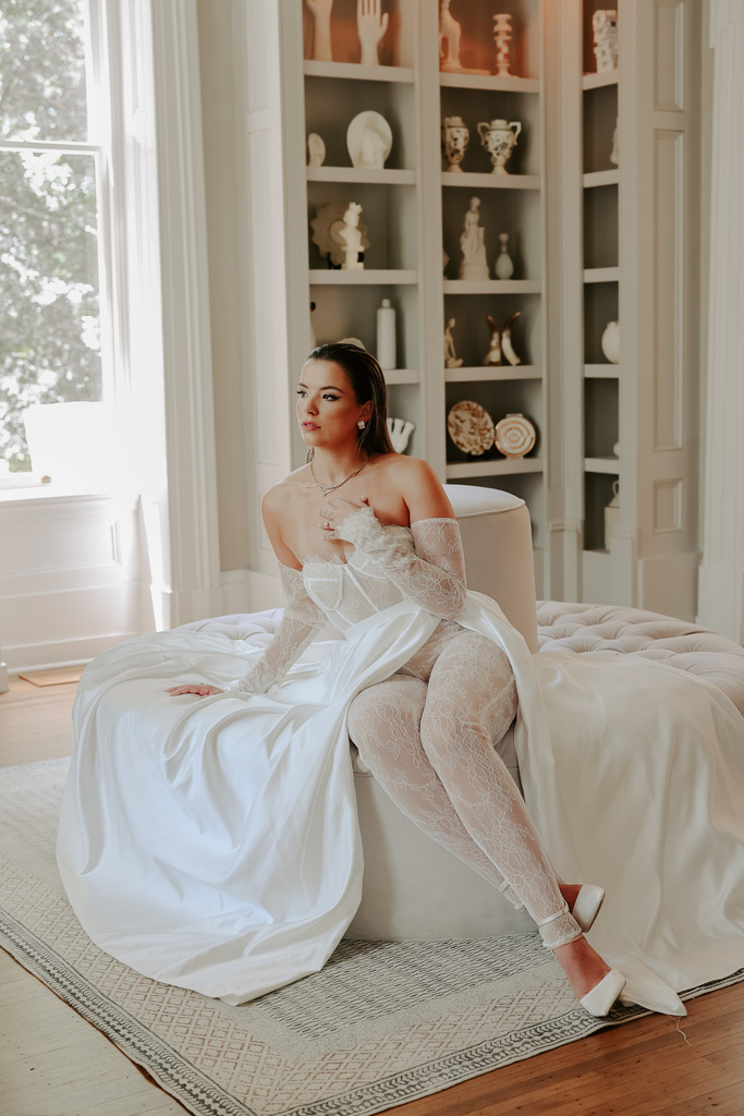 a person in a white wedding dress sitting on a bed