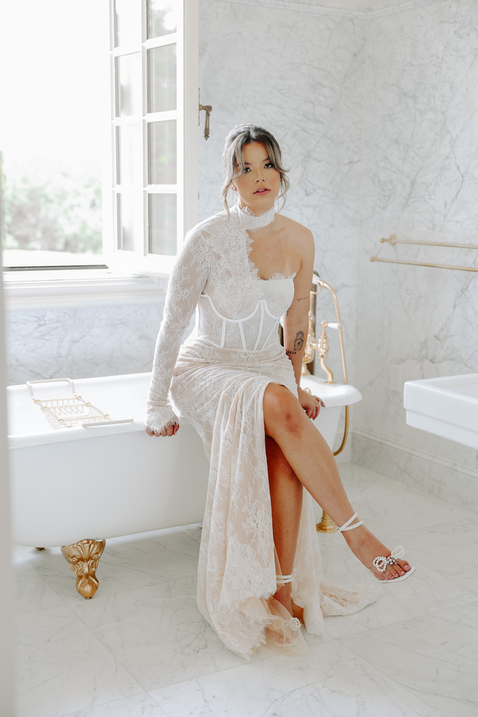 a person in a wedding dress sitting on the edge of a bathtub