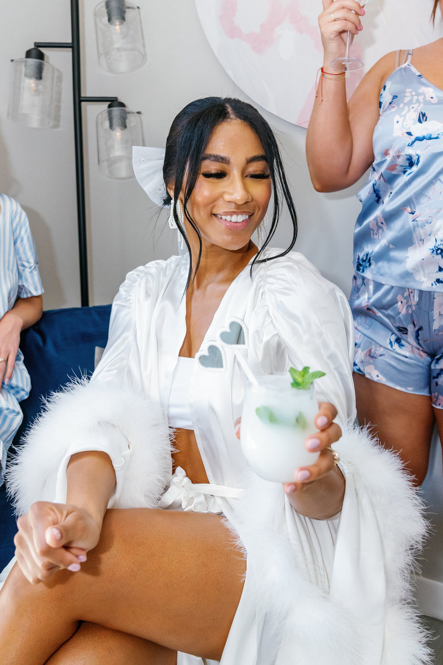 Three individuals in pajamas sitting on a couch holding drinks