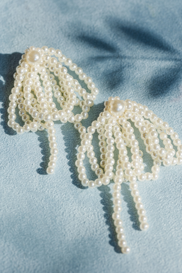 a pair of earrings with pearls hanging from them