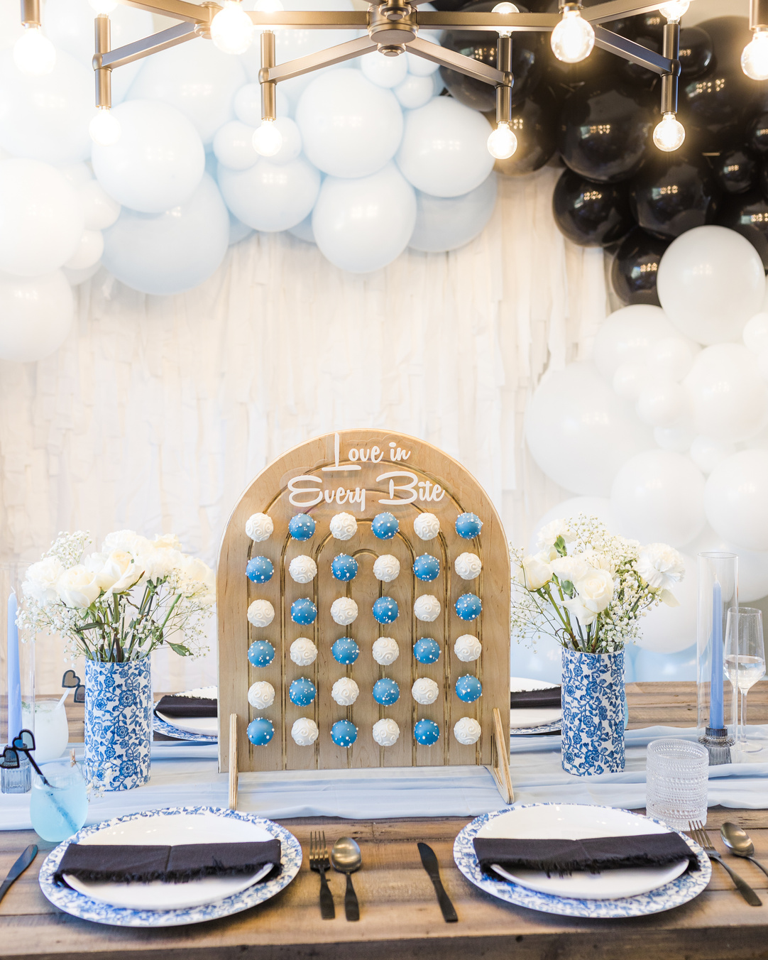 a table set up with blue and white place settings and cake pop