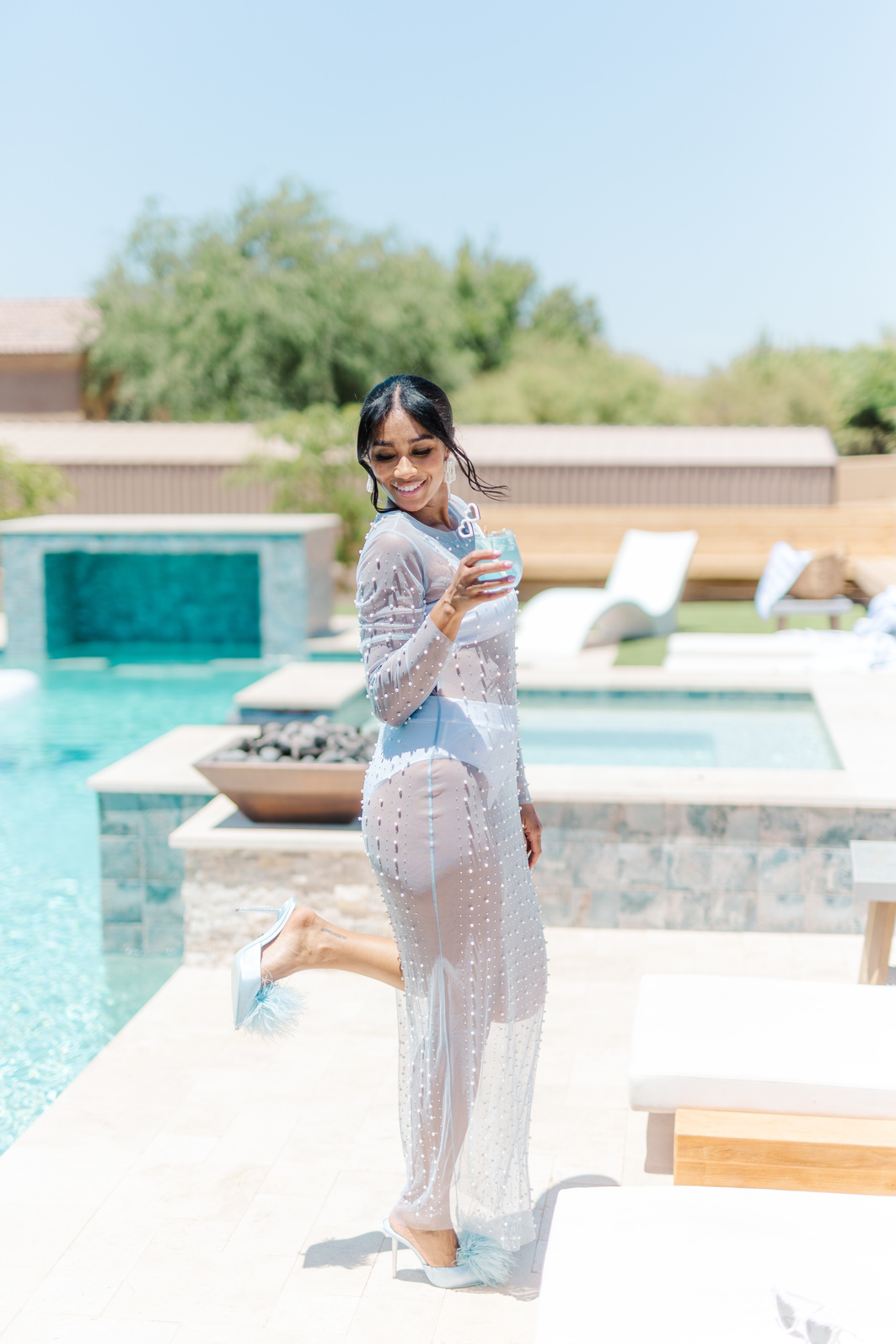 a person in a light blue dress standing next to a pool