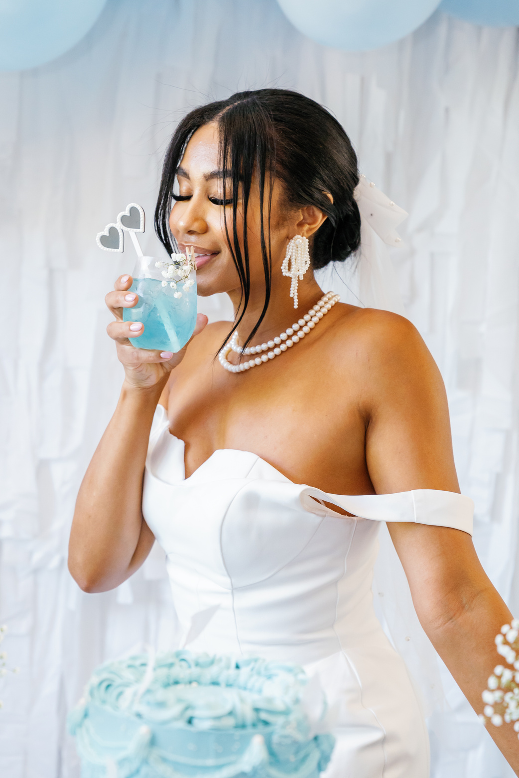 a person in a white dress drinking from a blue drink