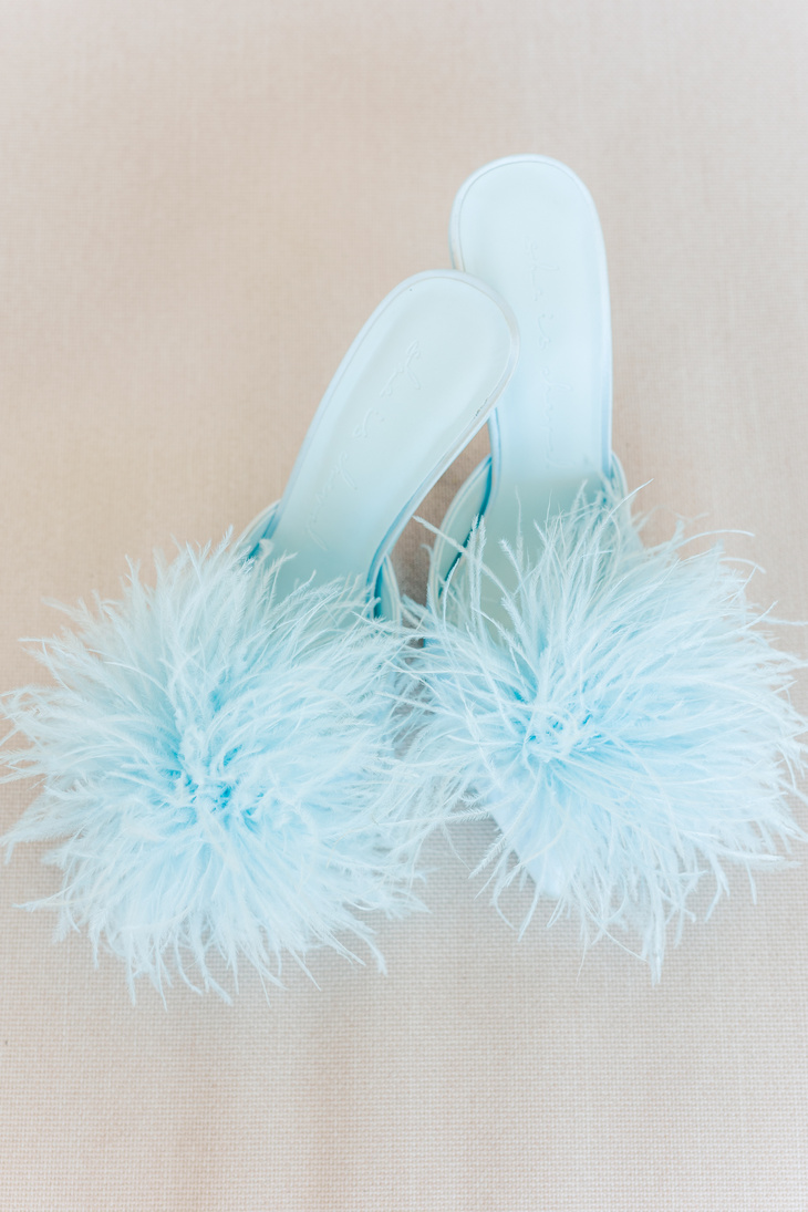 a pair of light blue shoes with fluffy pom poms