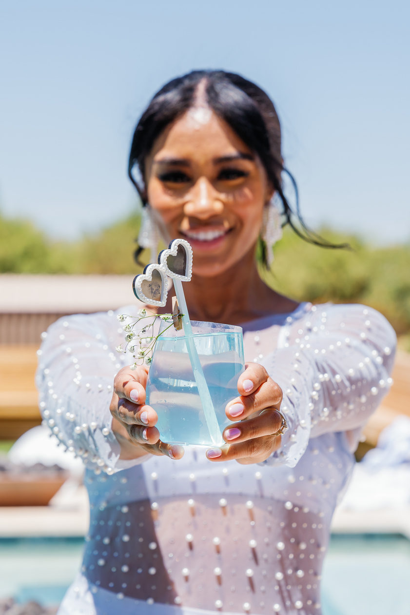 a person in a white dress holding a blue drink