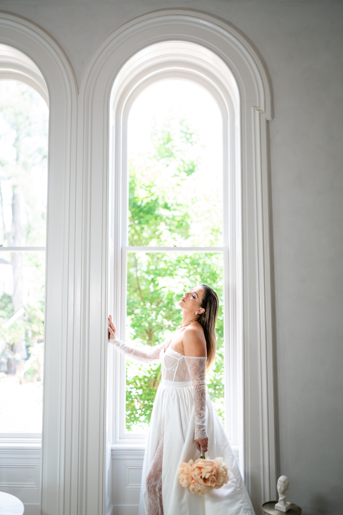 a bride in a white wedding dress standing in front of an arched window