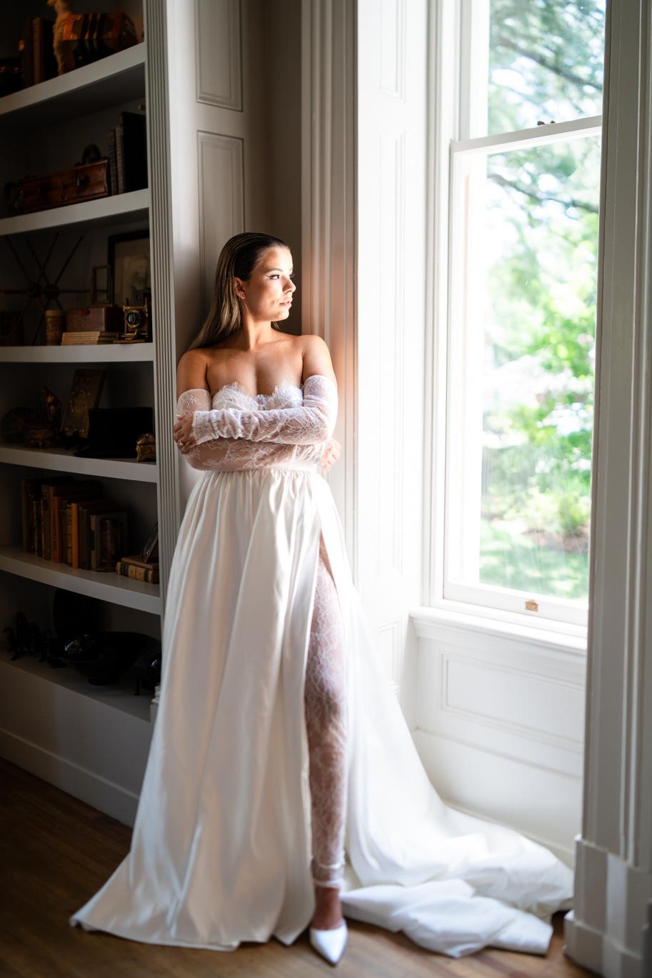 a person in a white dress standing in front of a window