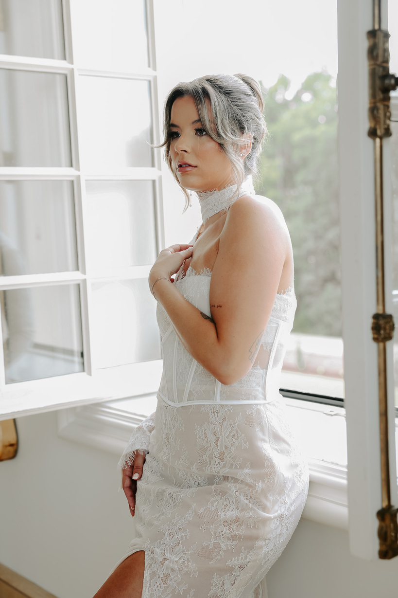 a person in a wedding dress is standing in front of a window