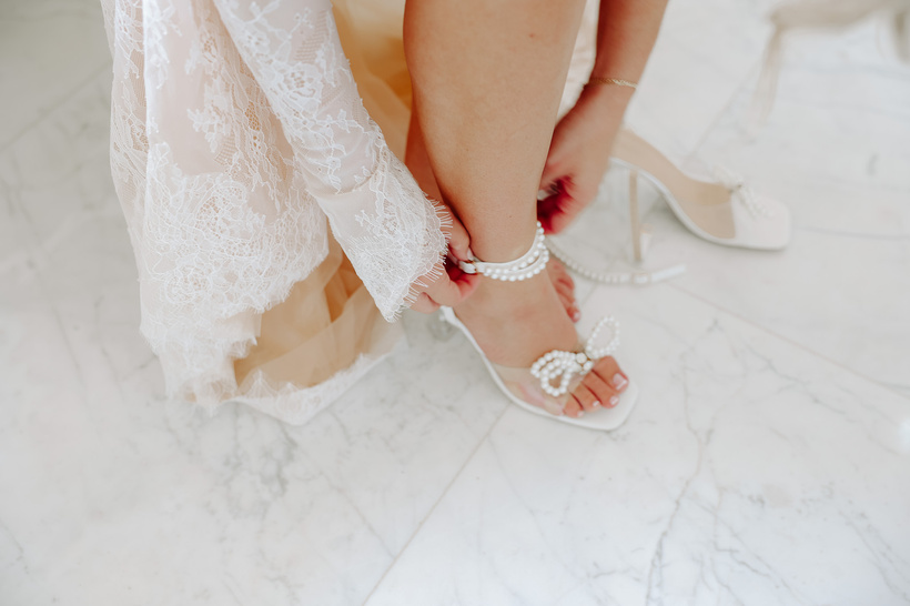 a person in a wedding dress putting on their wedding shoes