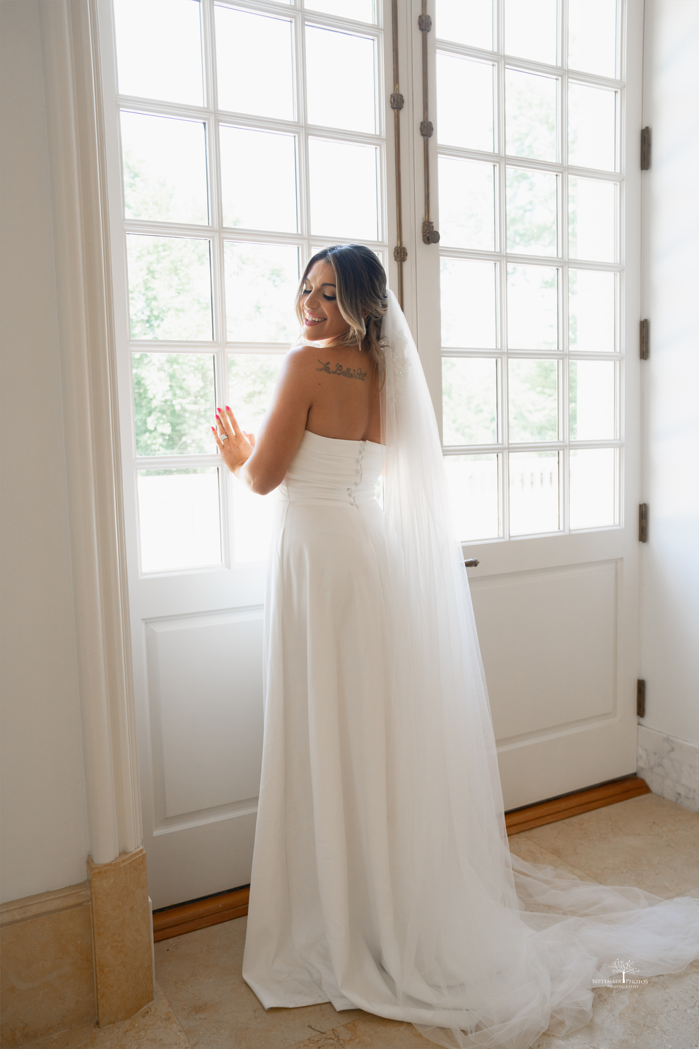 a bride in her wedding dress standing in front of a large window